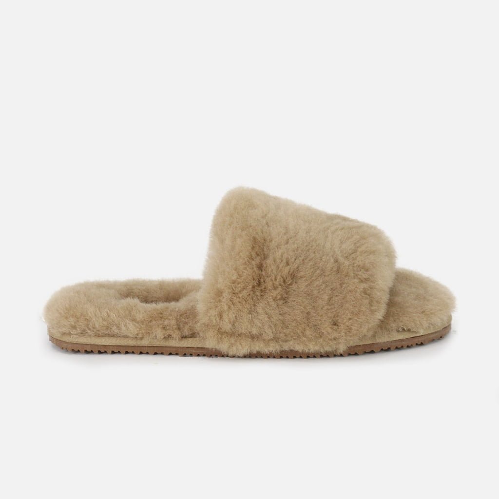 A personalized one-strap slide slipper in warm beige, constructed with genuine sheepskin and tailored for individual fit.